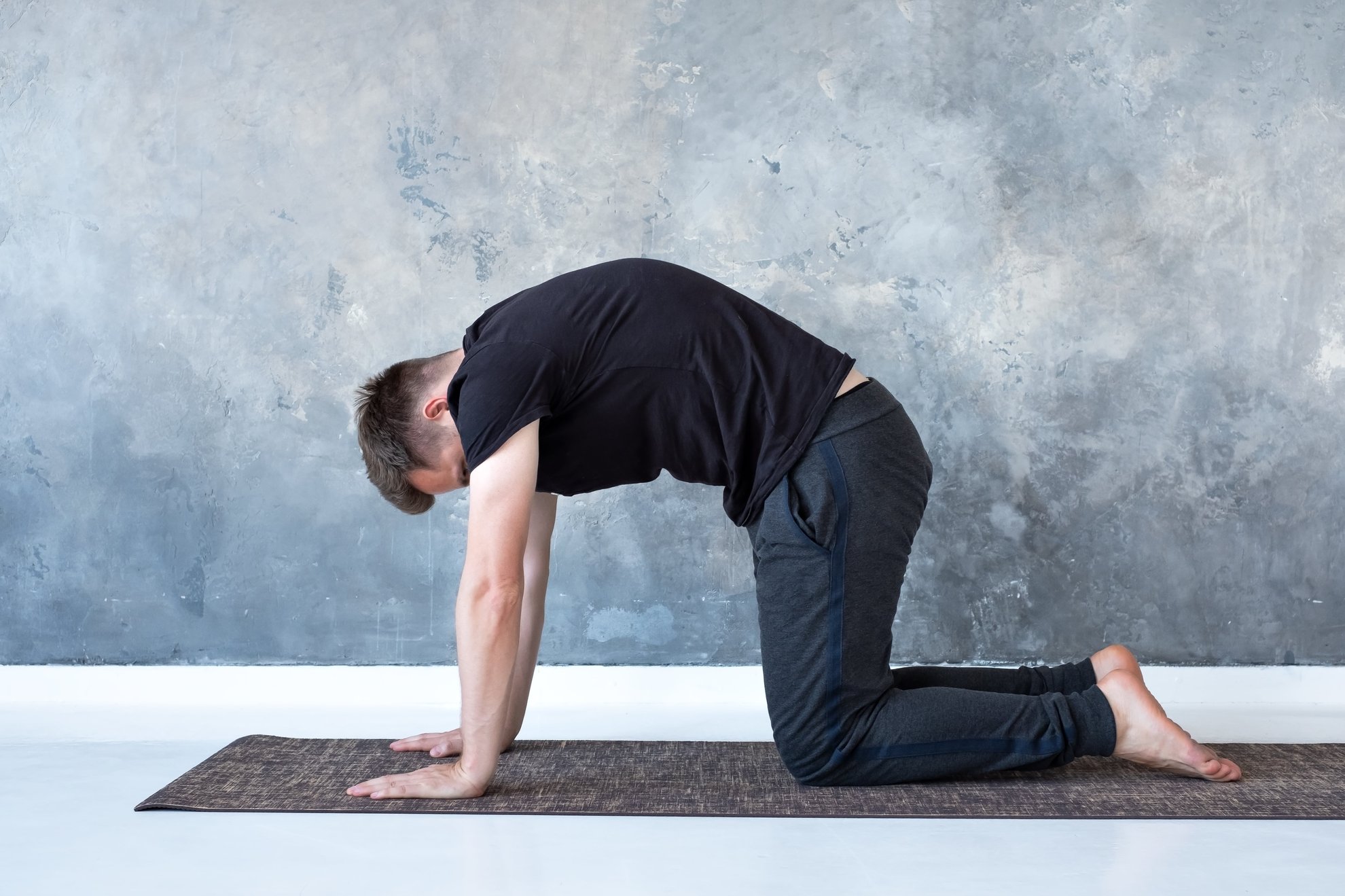 uomo che fa yoga per la cervicale nella posizione del gatto