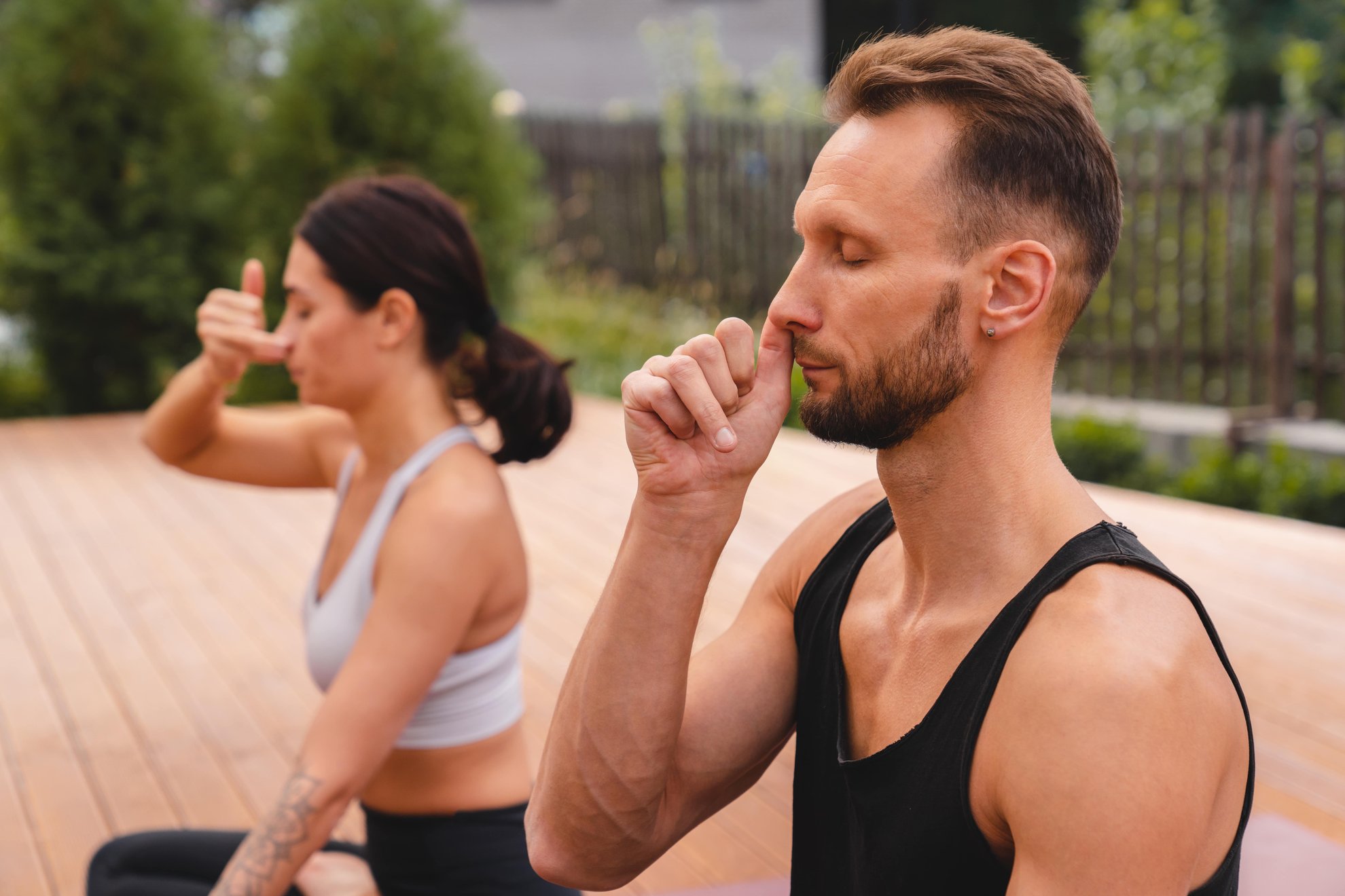 Foto ravvicinata di due yogi che respirano profondamente con una sola narice durante la lezione di yoga