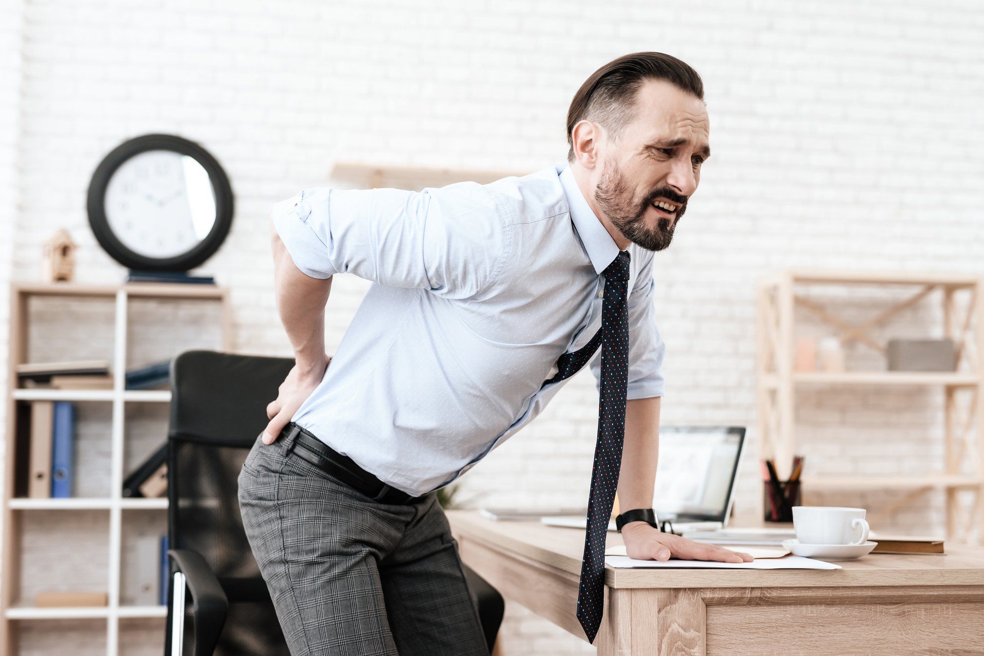 Man got up from chair and grabbed for a sore back.