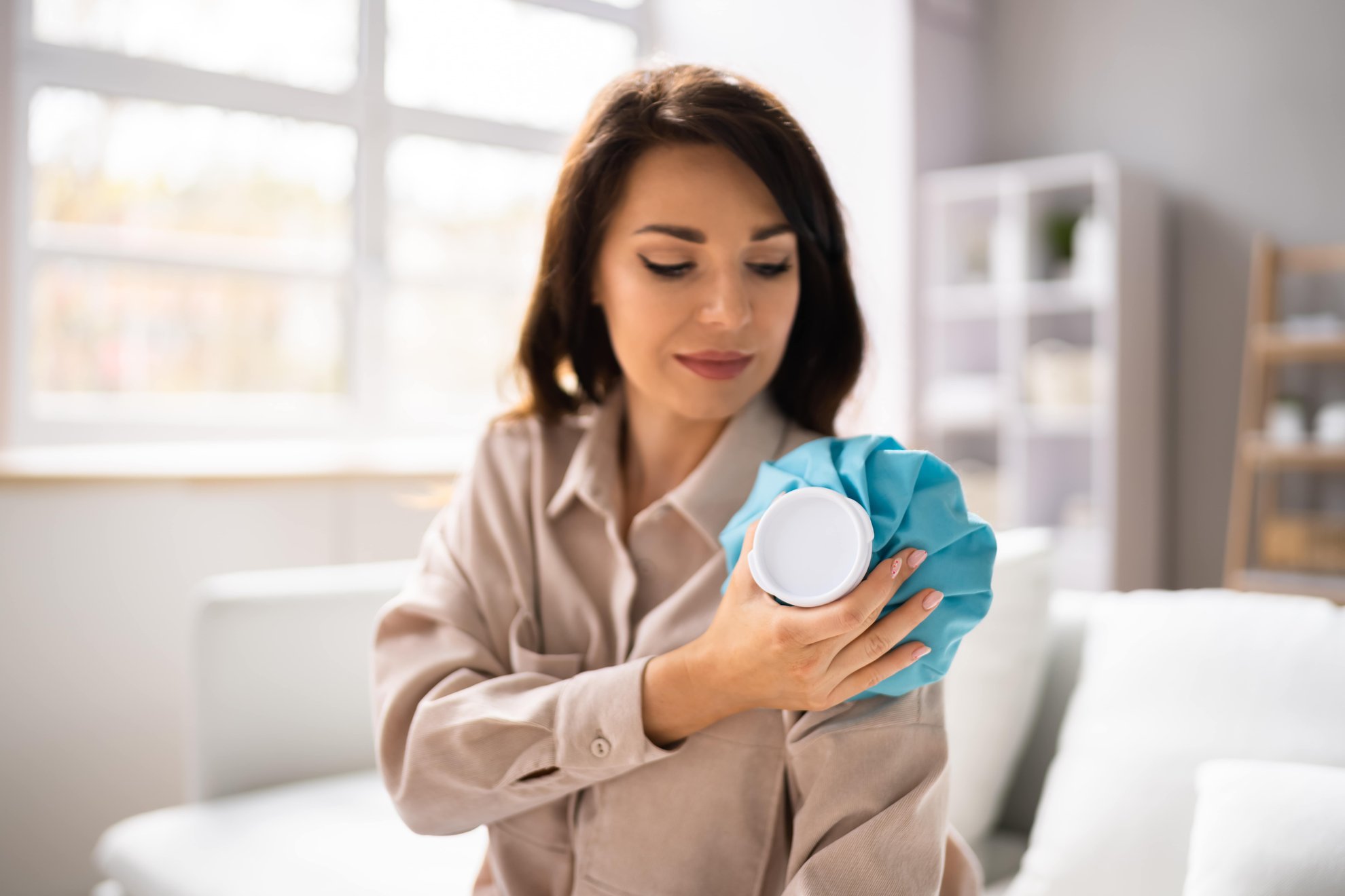 Donna applica un impacco freddo sulla spalla dolorante per alleviare l'infiammazione articolare.
