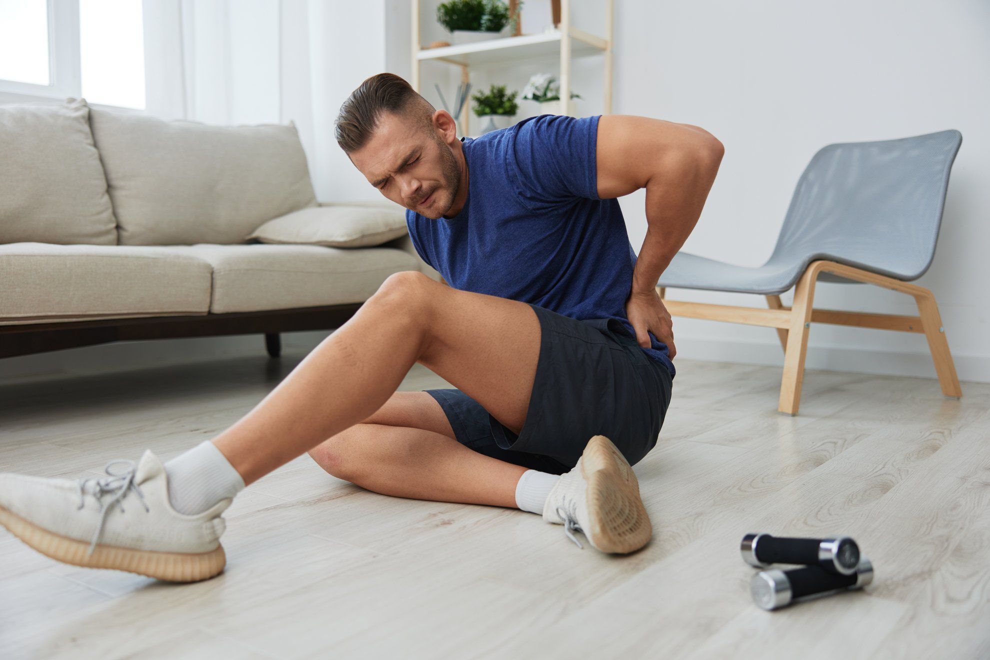 Man athlete pain and injury back arm and leg at home, sports injury bodybuilder, concept health and beauty